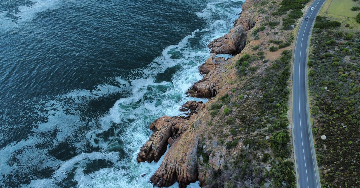Breathtaking aerial view of a coastal road along a rocky shoreline with waves crashing