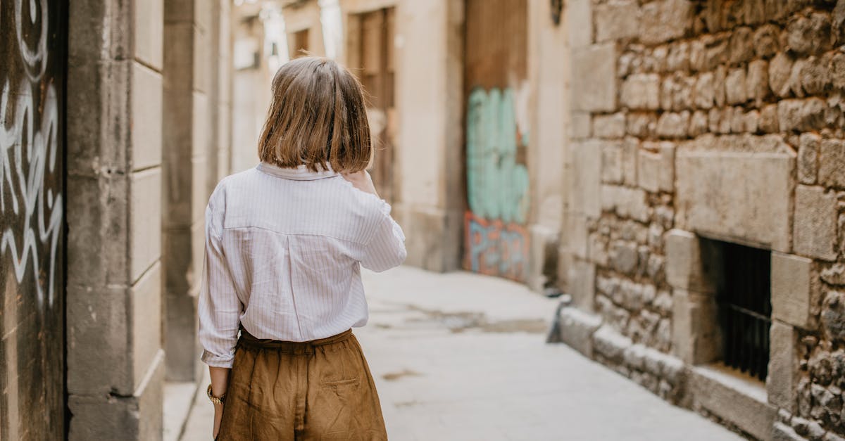 Woman in casual attire walks through a rustic urban alleyway during summer.