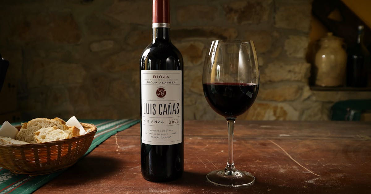 Luis Cañas wine bottle with a glass on a vintage wooden table, perfect for dining settings.