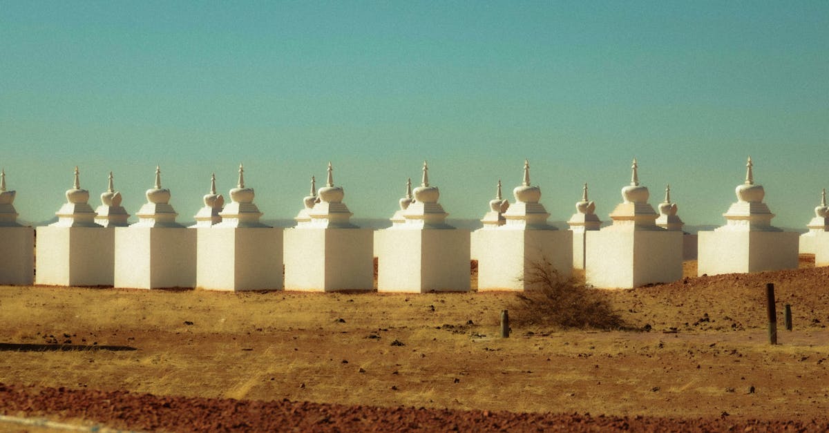 Row of white stupas in a tranquil desert setting under clear skies.