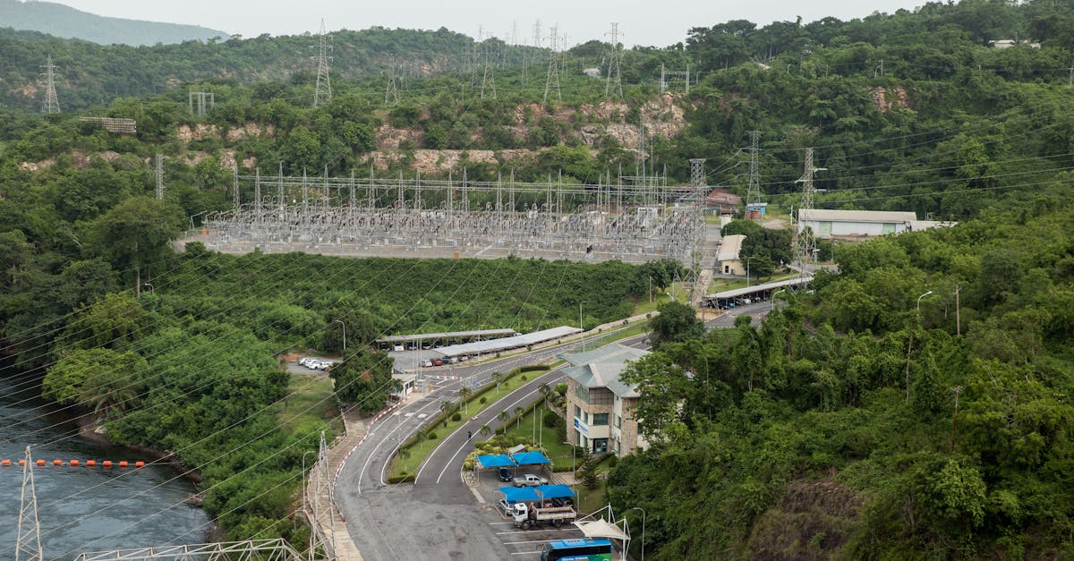 Aerial photograph showcasing a power station surrounded by lush green forest and river.