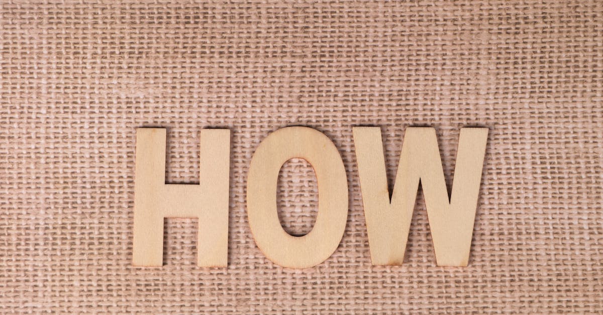 Word 'HOW' formed with wooden letters on textured burlap surface.