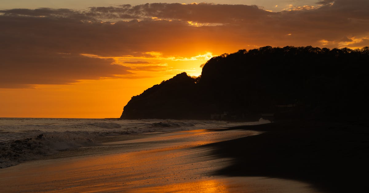 A breathtaking sunset over a tranquil beach in El Salvador with vivid orange hues.