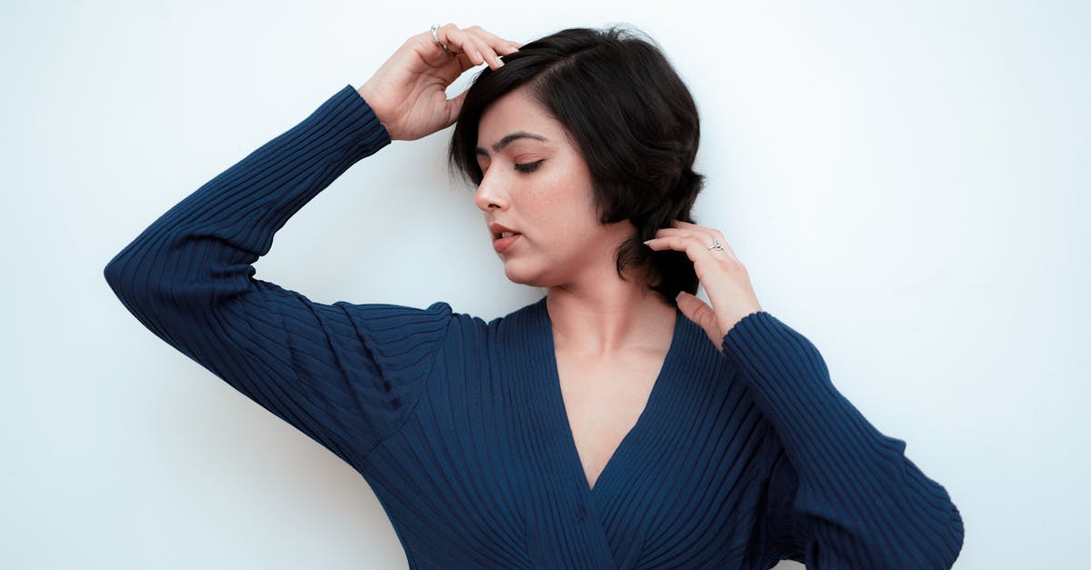 Serene portrait of a woman in a blue dress posing gracefully against white background.