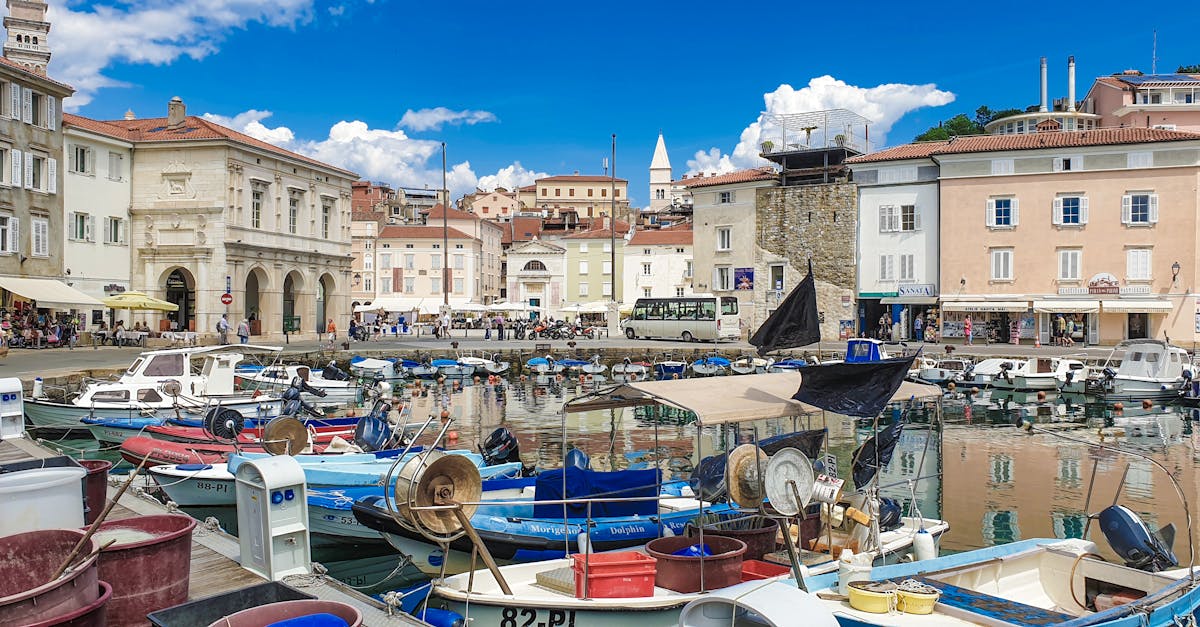 Vibrant harbor in Piran, Slovenia featuring boats and historic architecture under a clear blue sky.