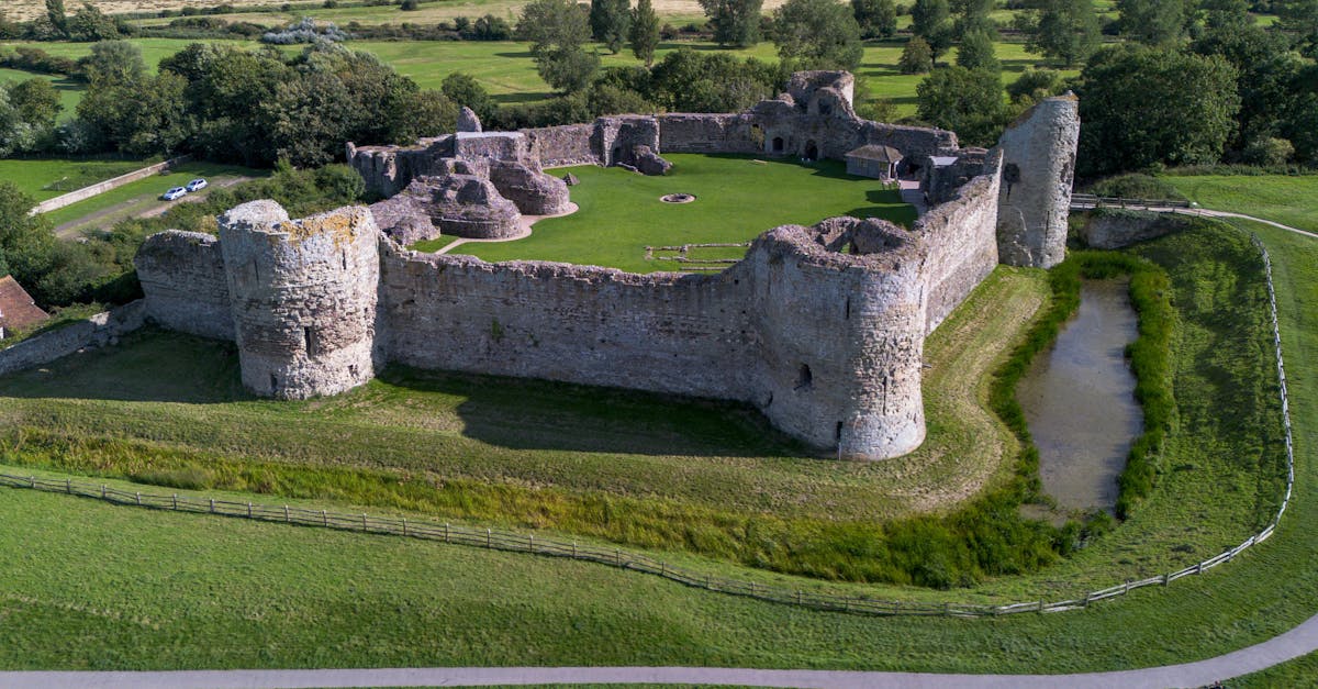 Aerial shot of medieval stone castle ruins surrounded by lush green countryside.