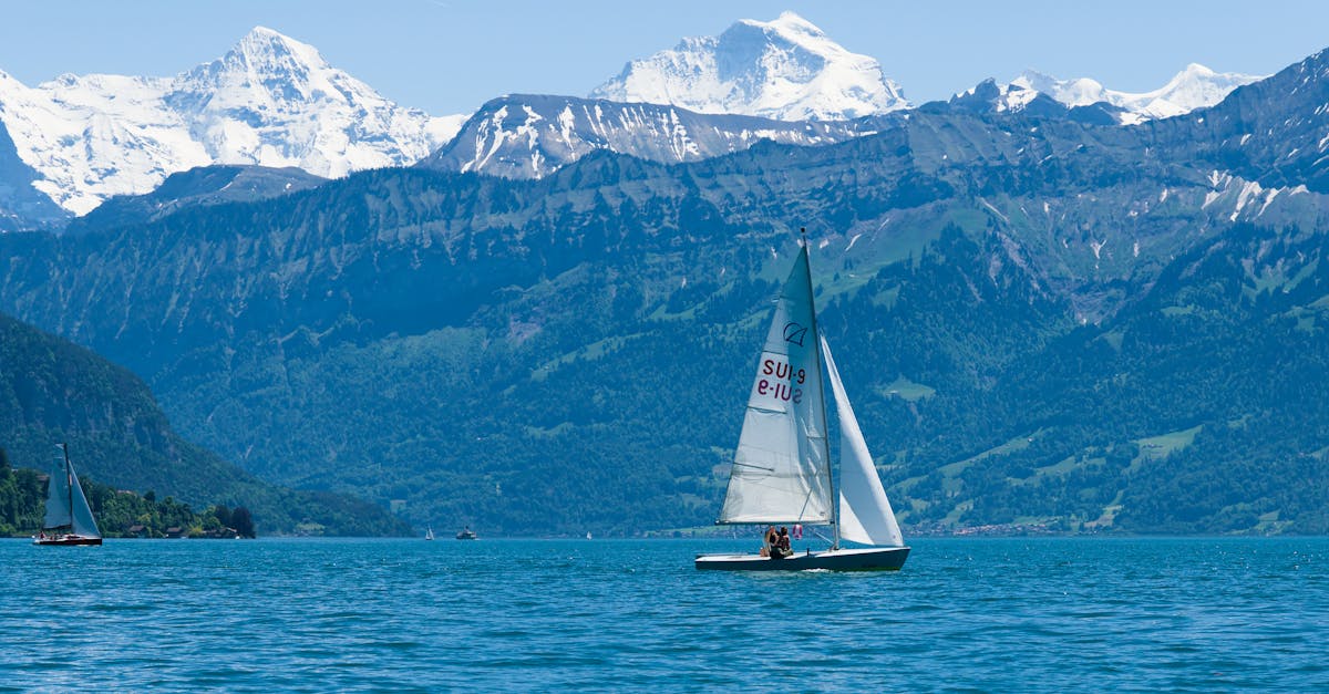 Serene view of a sailboat cruising on Lake Thun with the majestic Swiss Alps in the background.