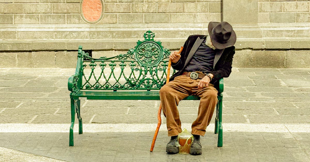 An elderly man in a hat resting on a park bench in Puebla, Mexico.