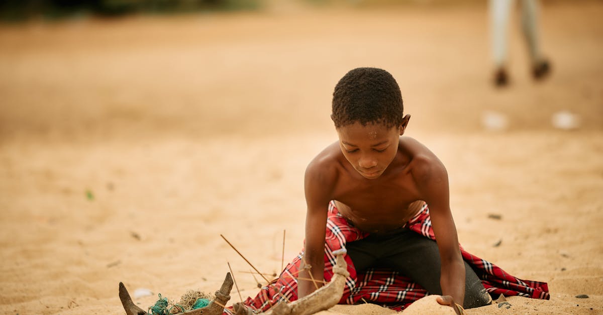 A young boy engaged in play on a sandy beach at Ada Foah, depicting local life in Greater Accra, Ghana.