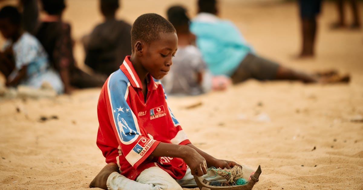 A young boy in Ada Foah, Ghana, plays in the sand on a beach, capturing the essence of local life.