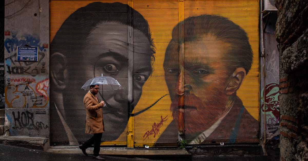 Graffiti of Van Gogh and Dali on an Istanbul wall with a man walking under an umbrella.