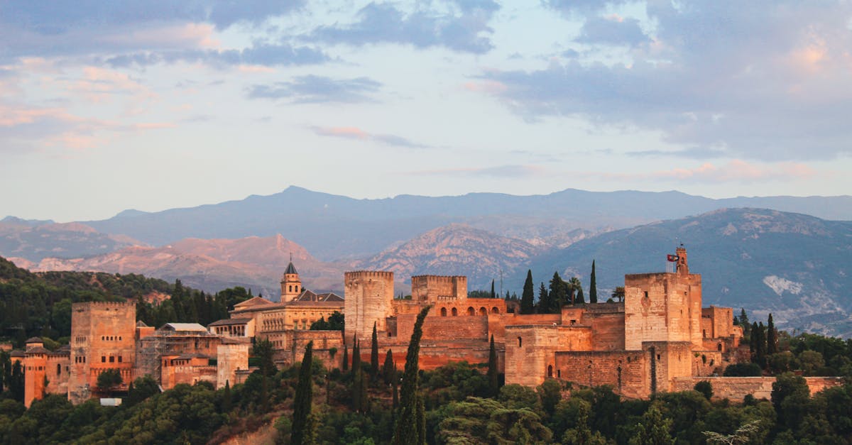 Majestic twilight view of Alhambra Palace in Granada, Spain against a mountain backdrop.