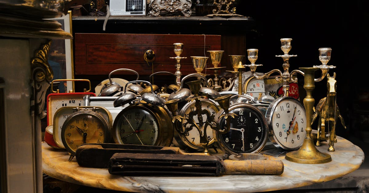 A collection of vintage alarm clocks and candlesticks on a marble table in a rustic setting.