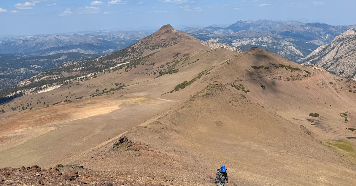A solitary hiker trekking along the rugged Sierra Nevada mountains under a clear sky.