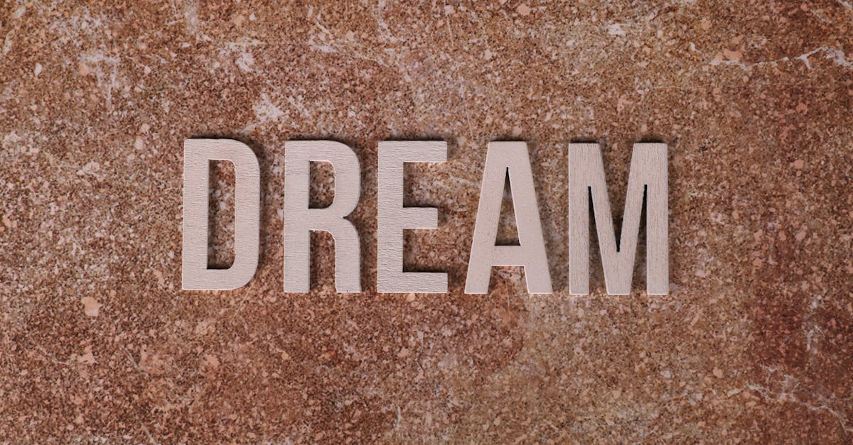 Wooden letters spelling DREAM on textured marble background for motivation.
