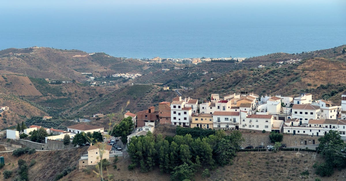 A scenic view of a Spanish hilltop village overlooking Mediterranean Sea, captured in evening light.