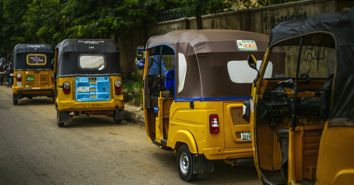 Auto rickshaws parked on a quiet street in Kaduna, Nigeria, showcasing vibrant colors and local life.