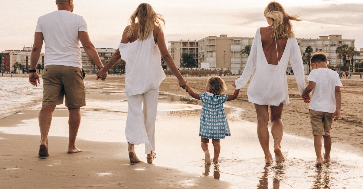 Family walking hand in hand along the beach at sunset, enjoying a warm summer day.