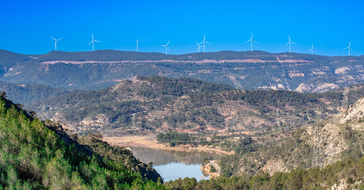 Picturesque landscape of a wind farm in Cofrentes, Spain with lush greenery and clear blue sky.