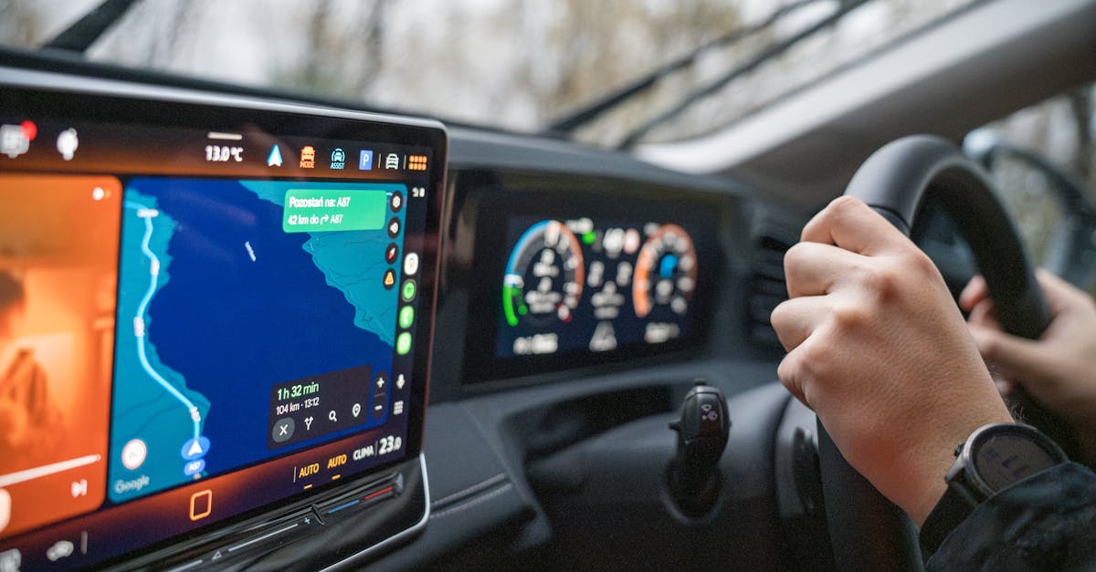 Close-up of hands on steering wheel and GPS navigation on car dashboard, showcasing modern driving technology.