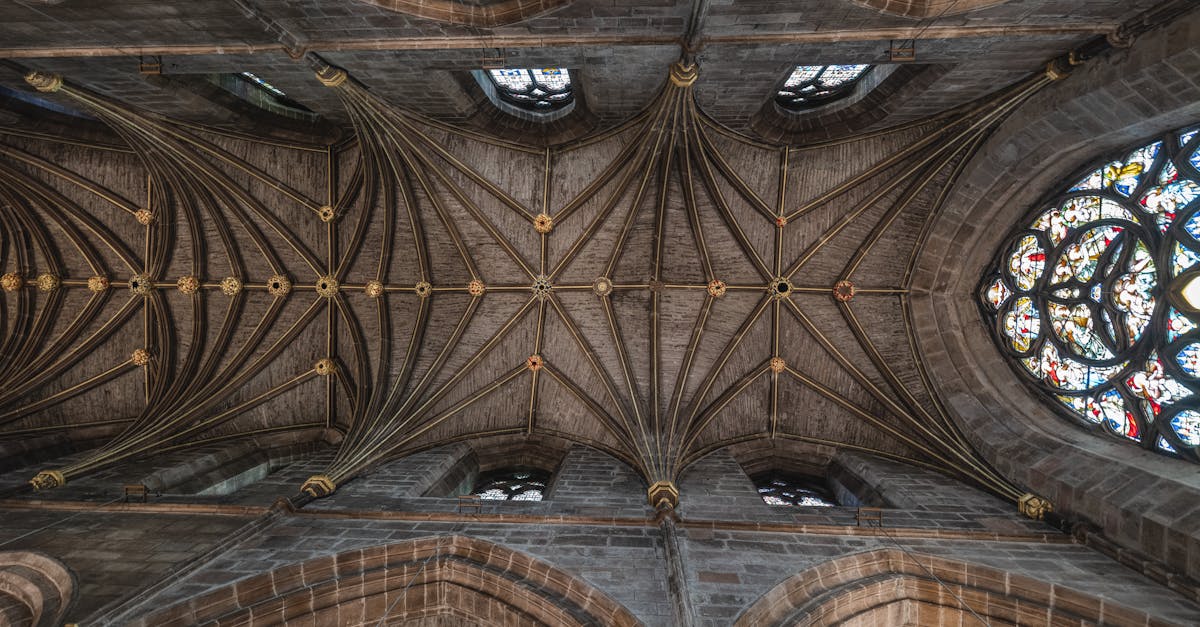Intricate Gothic cathedral ceiling featuring ornate arches and vibrant stained glass windows.