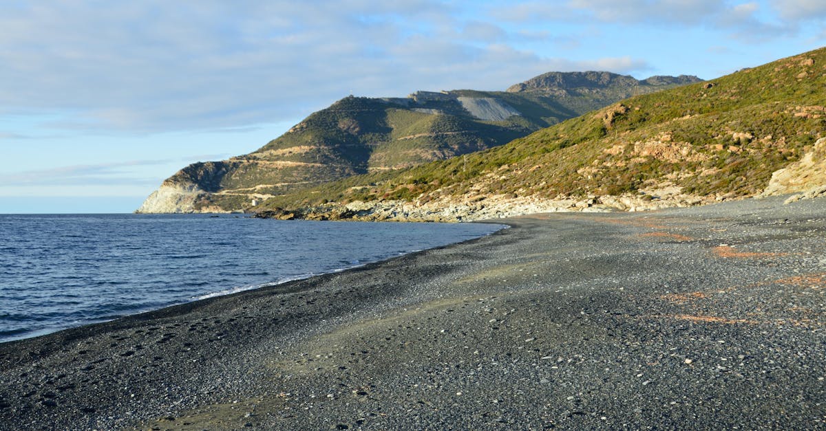 Beautiful beach with mountain backdrop in Corse, France, under a sunny day.