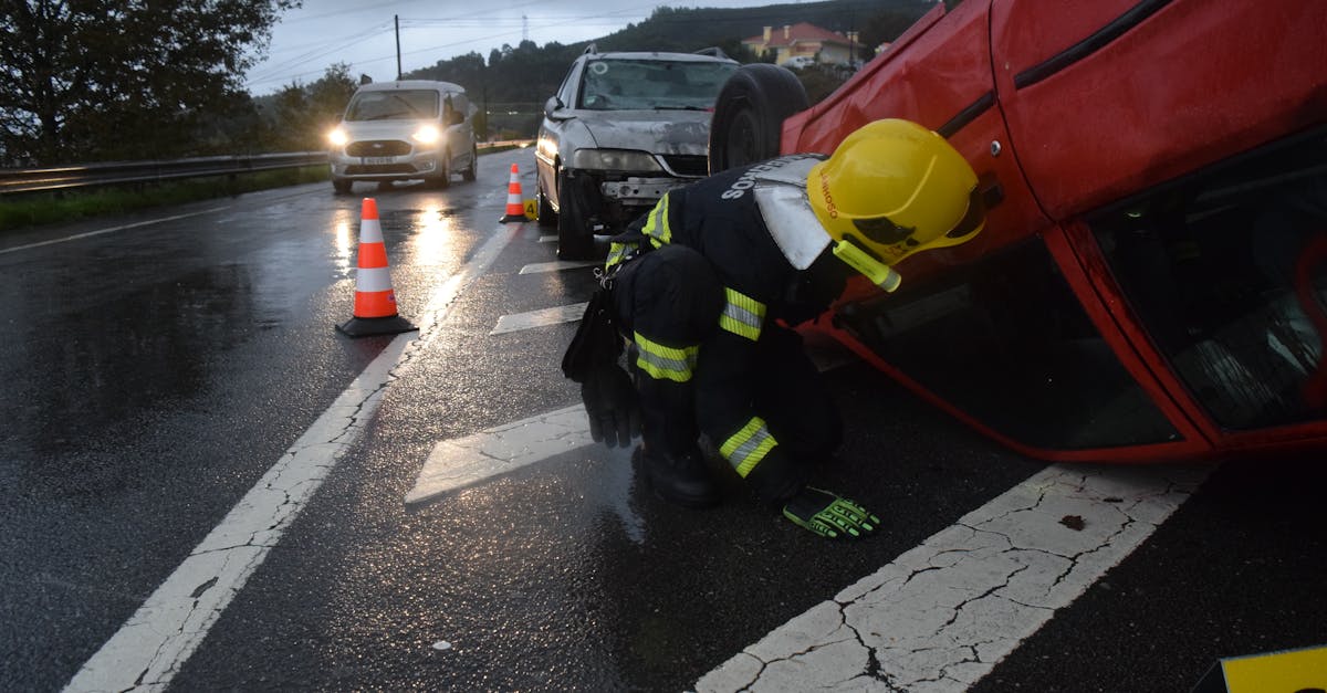 Firefighter attending to an overturned car on a rainy road in Póvoa de Lanhoso, Braga, Portugal.