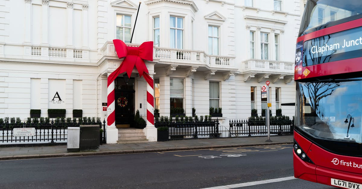 A decorated London townhouse with a giant red bow, featuring a passing red double-decker bus.