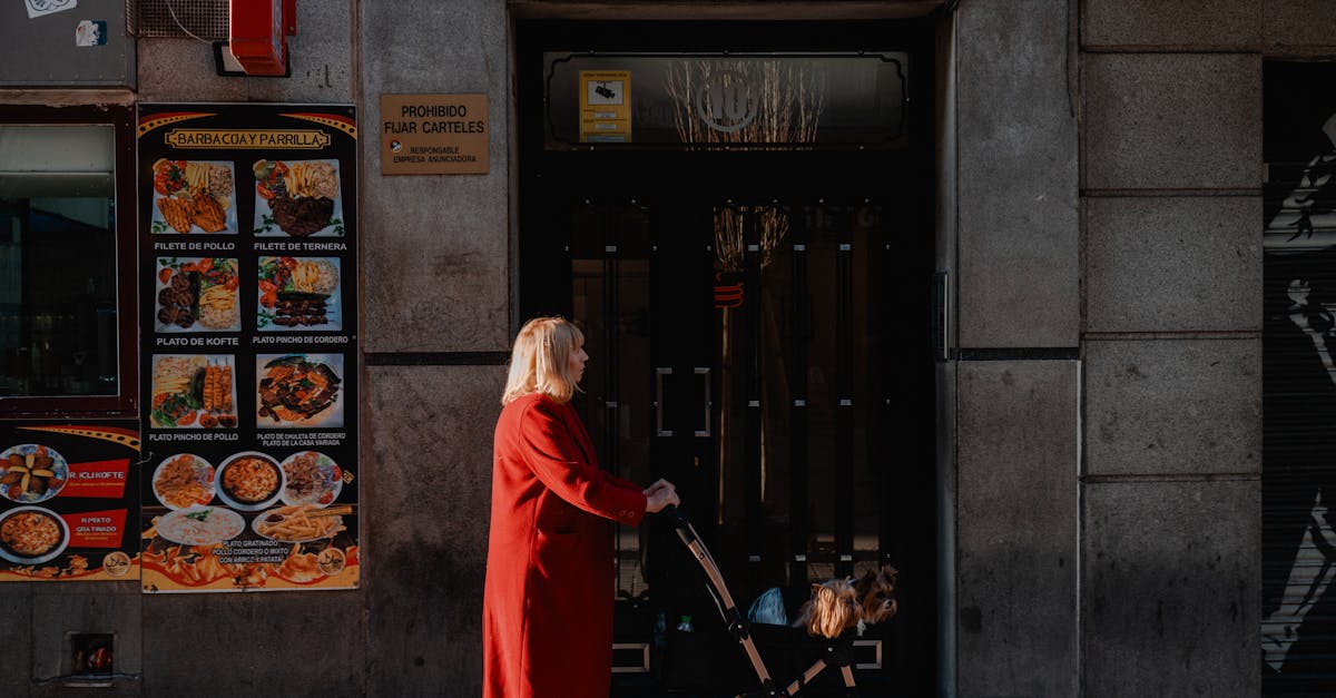 Woman in red coat walking with stroller on a sunny day in Madrid, Spain.