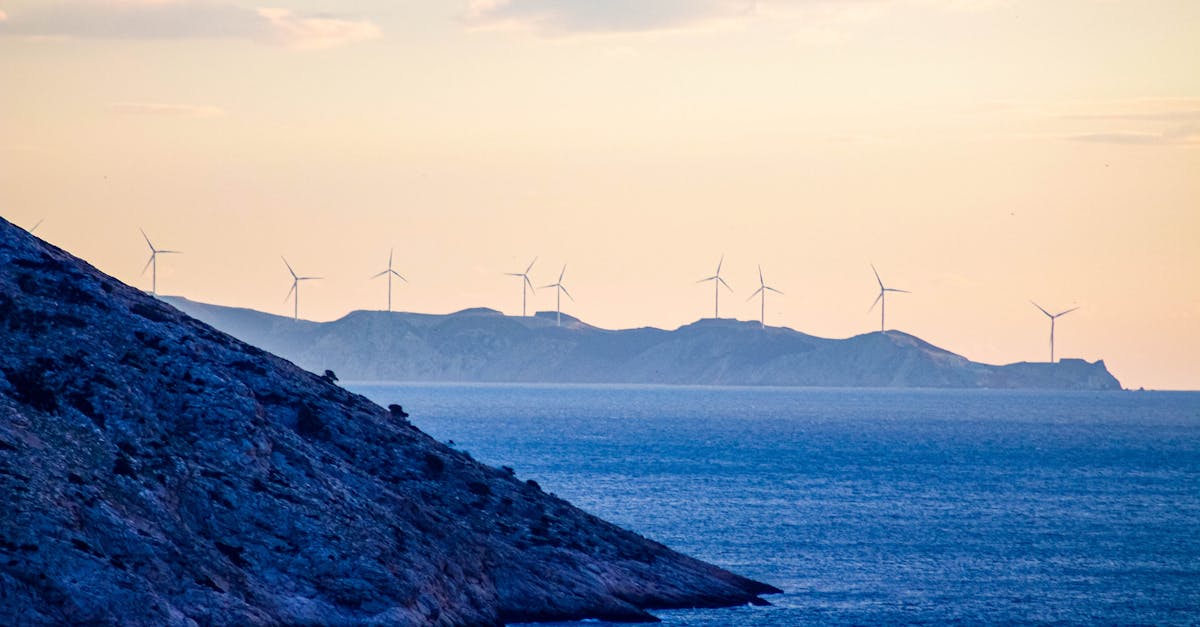 Beautiful coastal landscape with distant wind turbines and a serene sunset over the ocean.