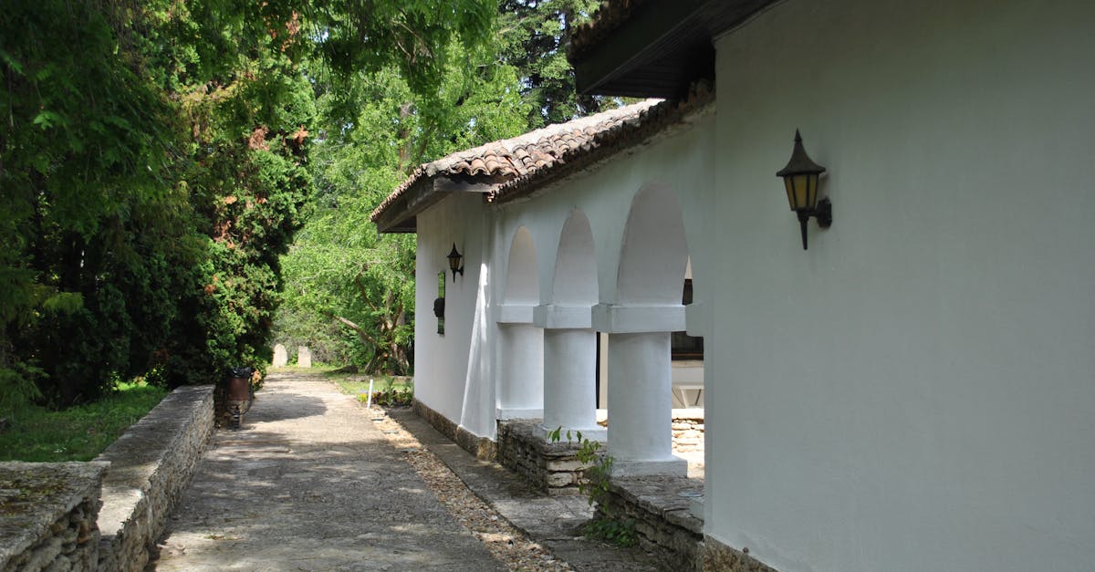 Charming historic building with arches framed by lush greenery and sunlight.