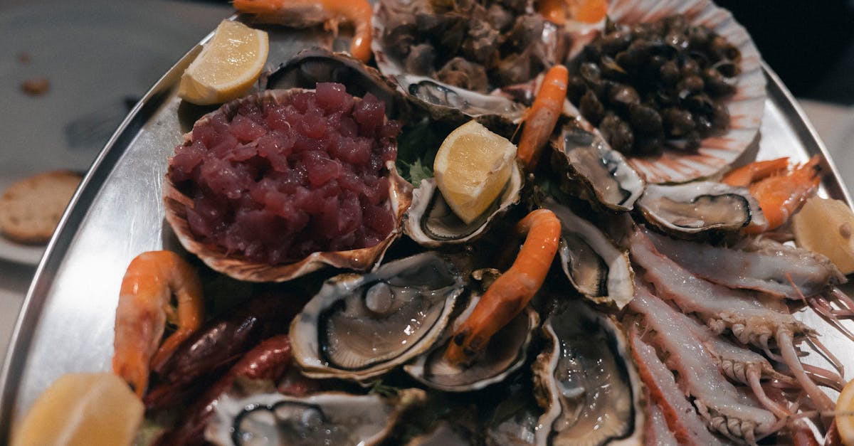 A beautifully arranged seafood platter featuring oysters, prawns, and tuna tartare with lemon garnish.