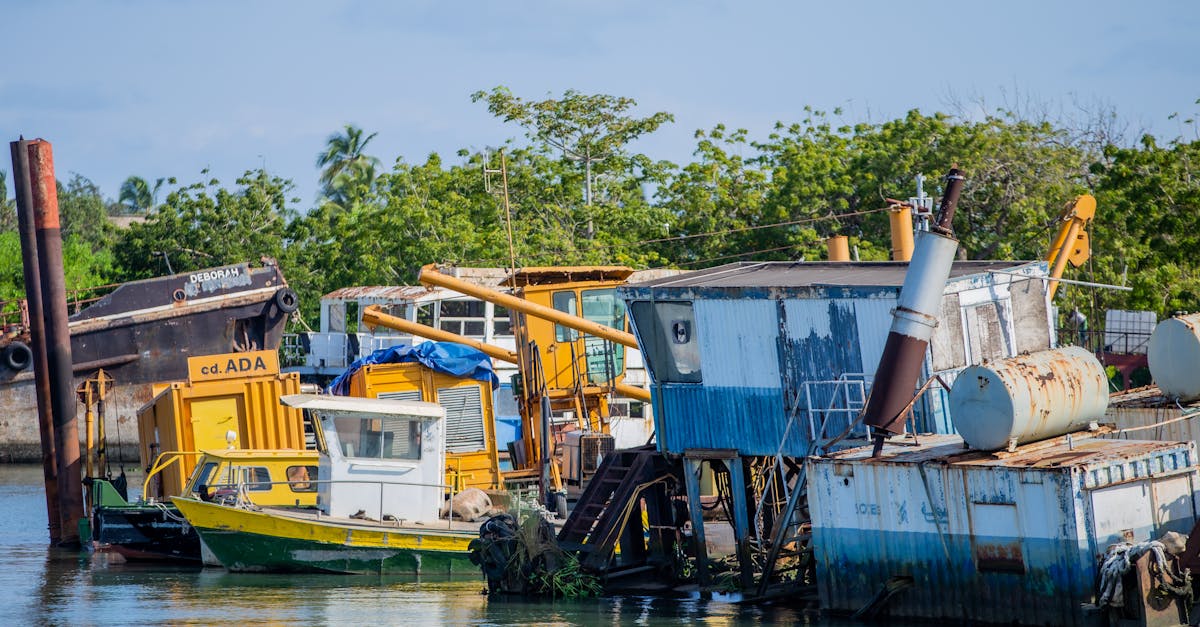 Colorful abandoned boats and equipment in a lush estuary setting.