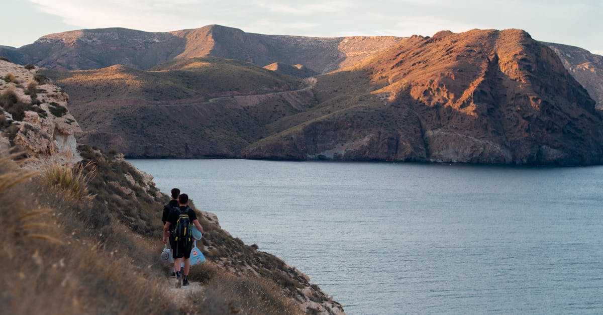 Two hikers traverse a coastal trail with stunning mountain and ocean views.
