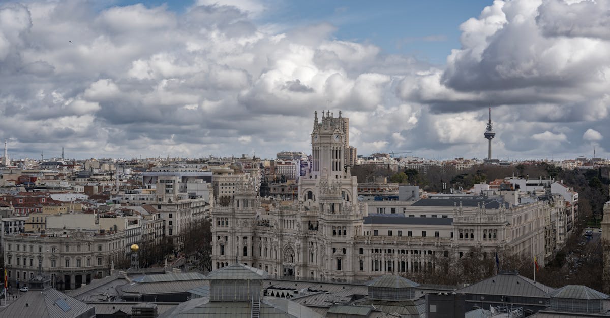 Aerial view of Madrid featuring the prominent Palacio de Cibeles under a cloudy sky.