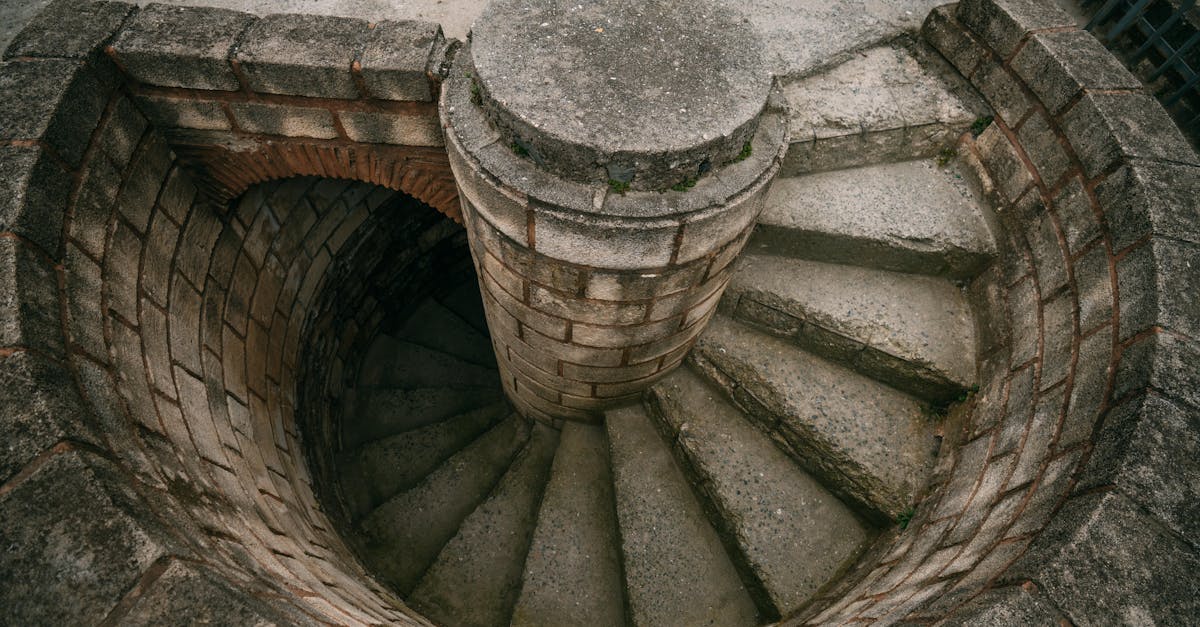 Top view of a spiraling stone staircase outdoors, showcasing architectural beauty.