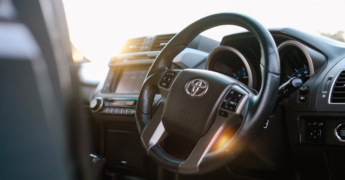 Close-up of a steering wheel and dashboard in a modern car with sunlight entering through the windows.
