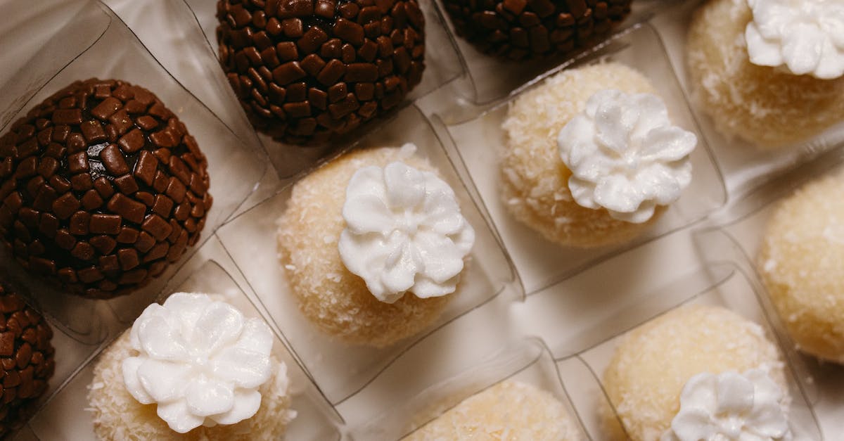 Top-down view of chocolate and coconut confections with decorative toppers arranged in a box.