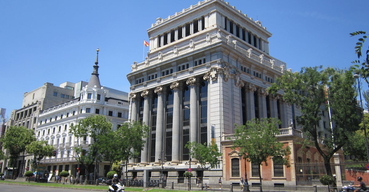 Grand buildings line a sunny street in Madrid, Spain, symbolizing urban elegance.