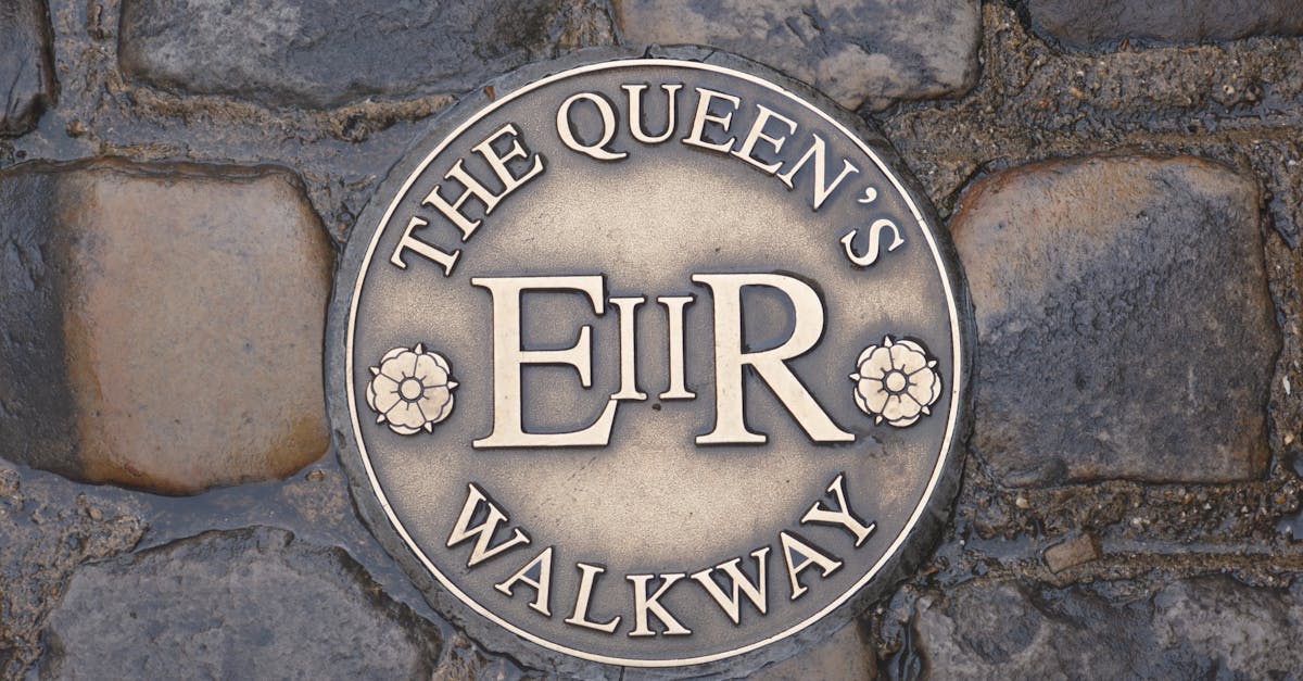 A detailed view of The Queen's Walkway plaque set in cobblestone in Windsor, England.
