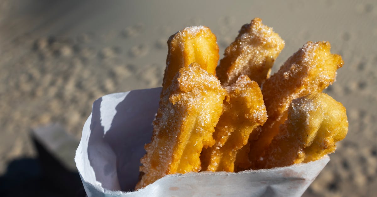 Close-up of crispy sugar-coated churros against a sandy beach background, evoking a sunny day in Montevideo.