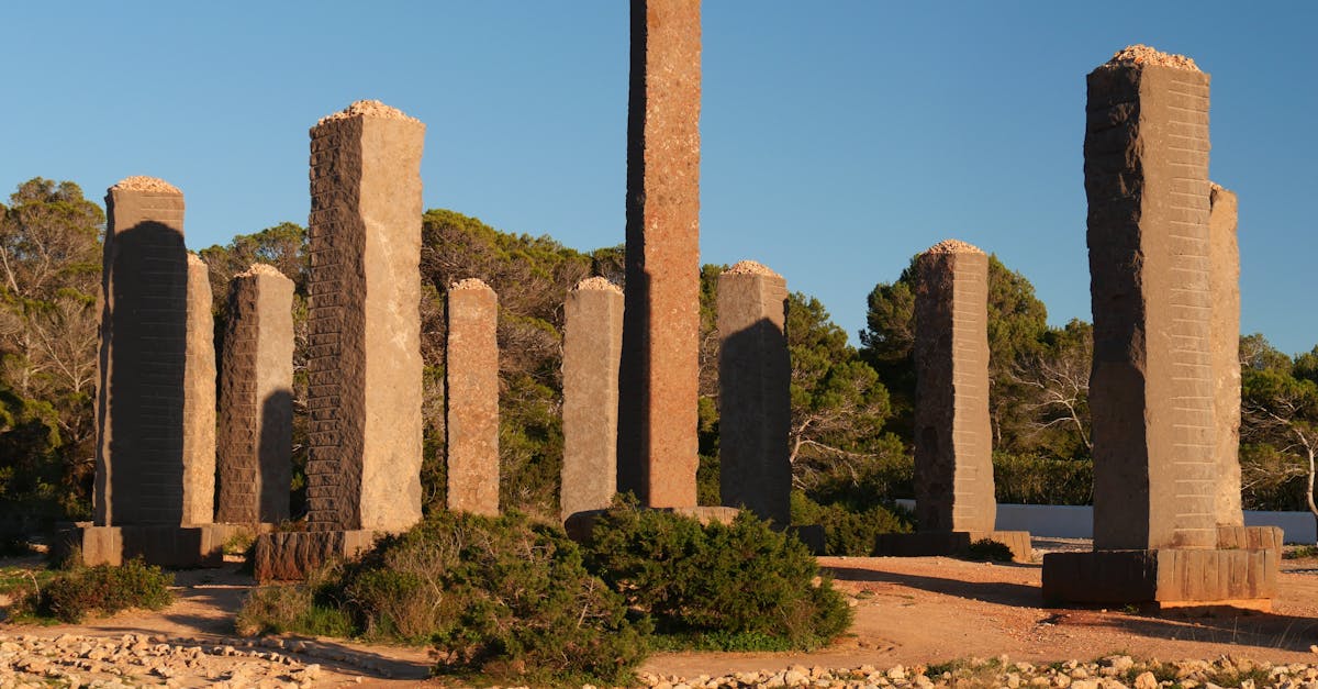 Ancient-like stone pillars standing in Ibiza, capturing a serene sunset with a clear blue sky backdrop.