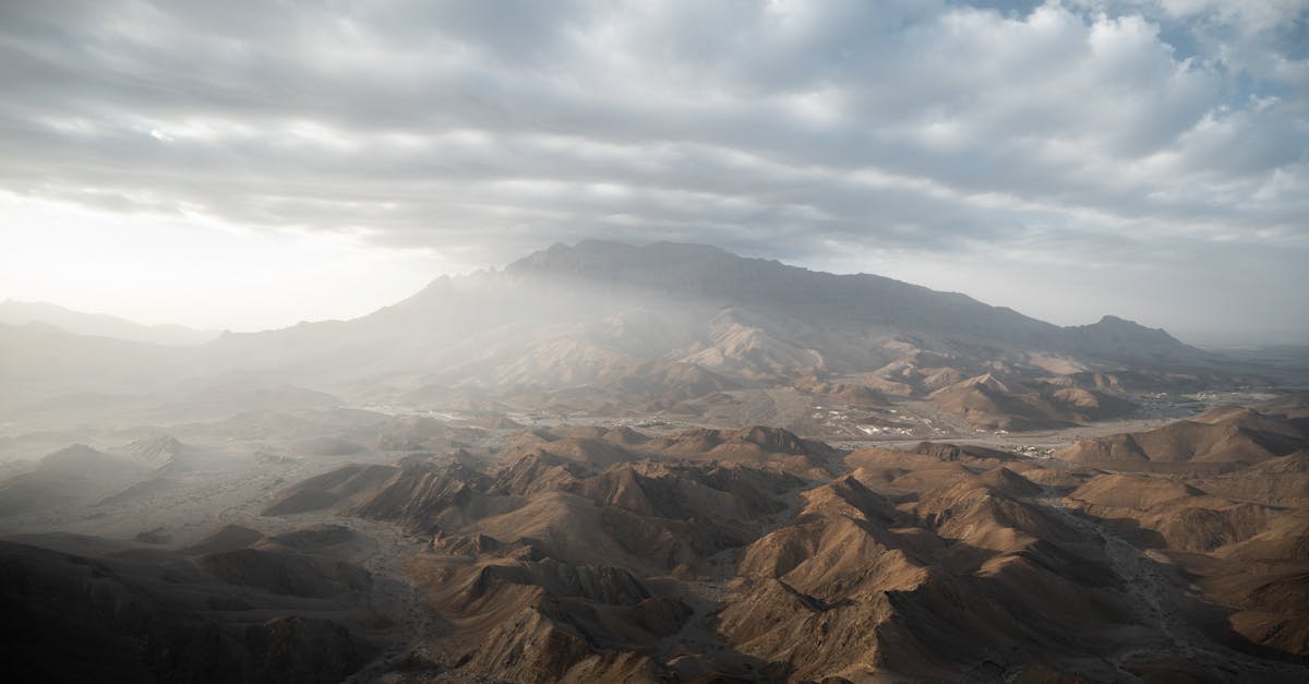 Stunning aerial landscape of mountains in Ad Dhahirah Governorate, Oman under a cloudy sky.