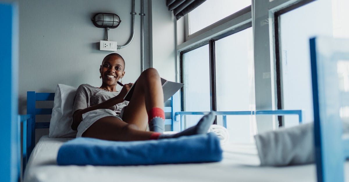 Woman in a cozy room writing on a bunk bed with natural light streaming in.