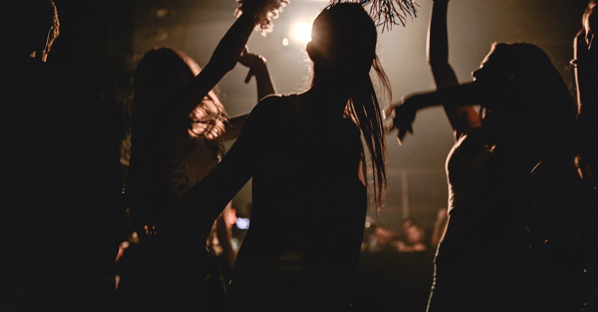 Silhouetted partygoers dancing with dynamic lighting at a lively club night.