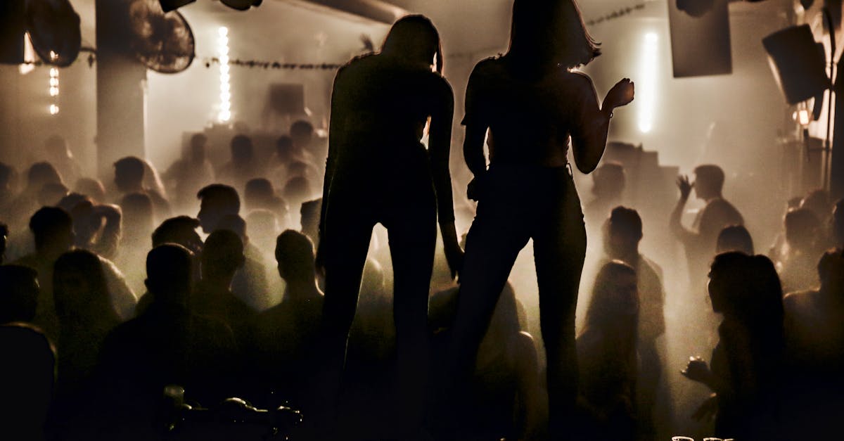 Silhouettes of women dancing in a lively nightclub with a smoky atmosphere.