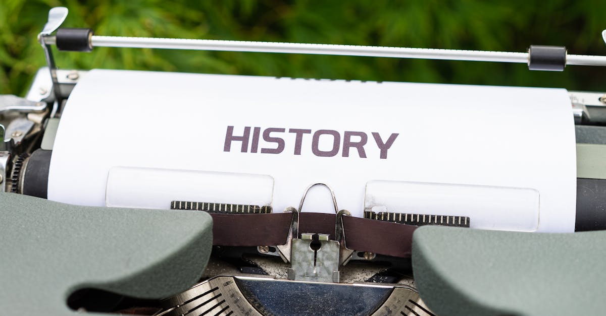 Close-up of a vintage typewriter with a paper labeled 'History' in an outdoor setting.