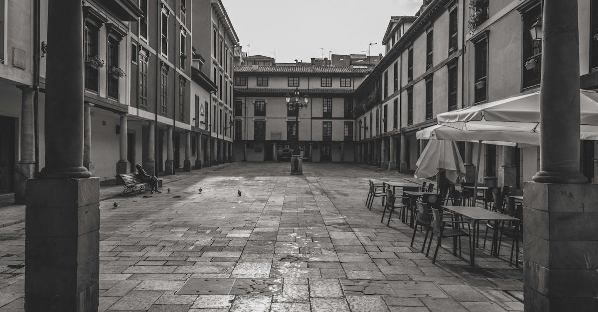 Monochrome view of a historic square with empty cafe tables in Oviedo, Spain.