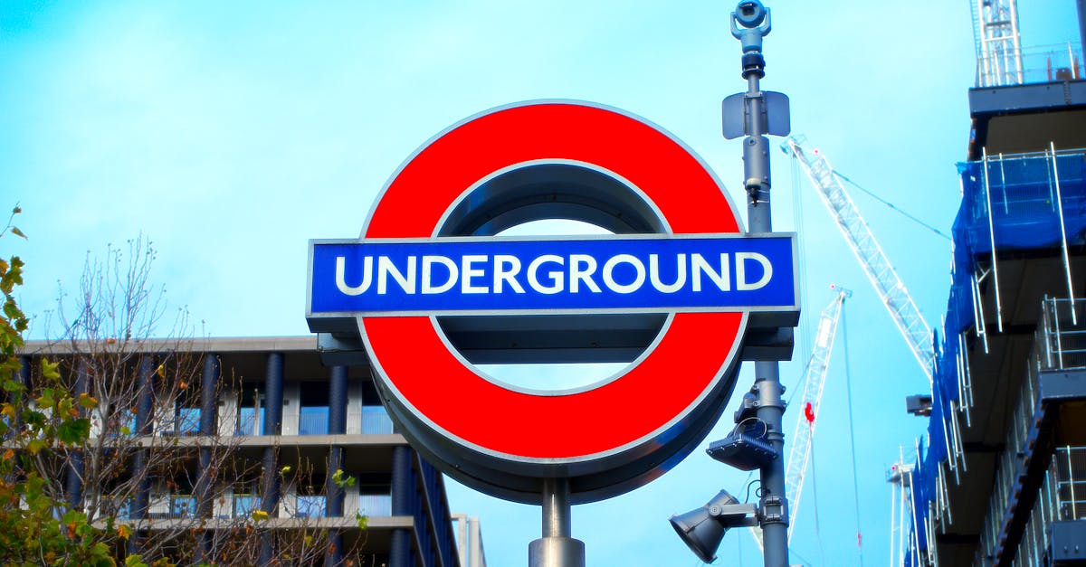 Bright and iconic London Underground sign with skyscrapers and construction cranes in the background.