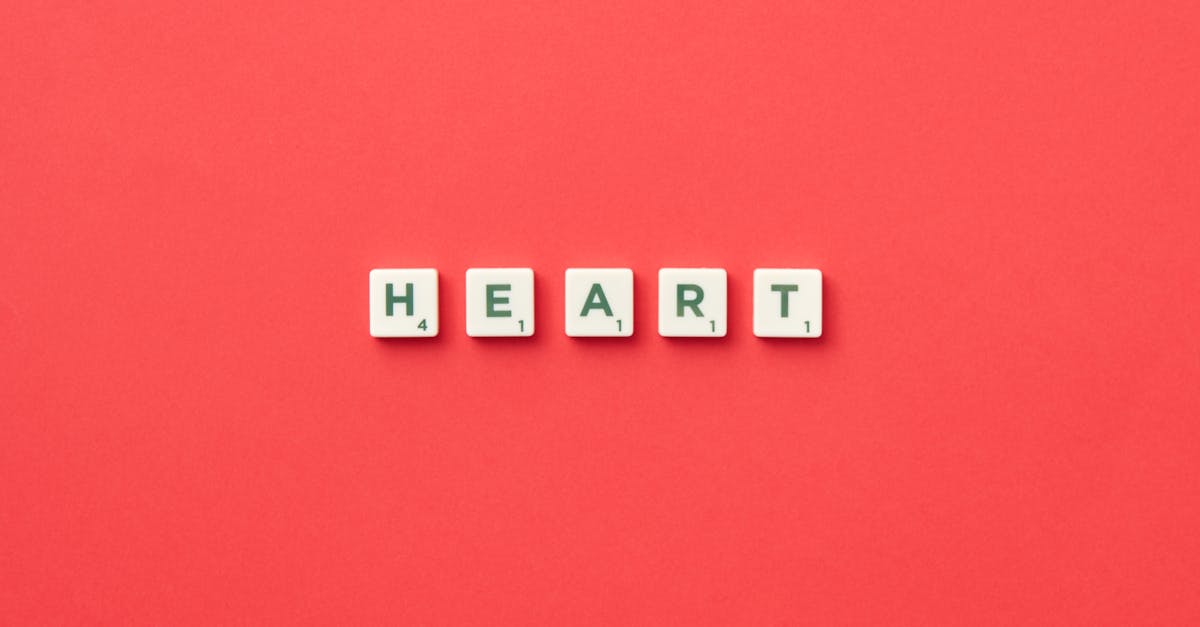 Top view of scrabble tiles spelling 'HEART' on a vibrant red background, perfect for love and games themes.